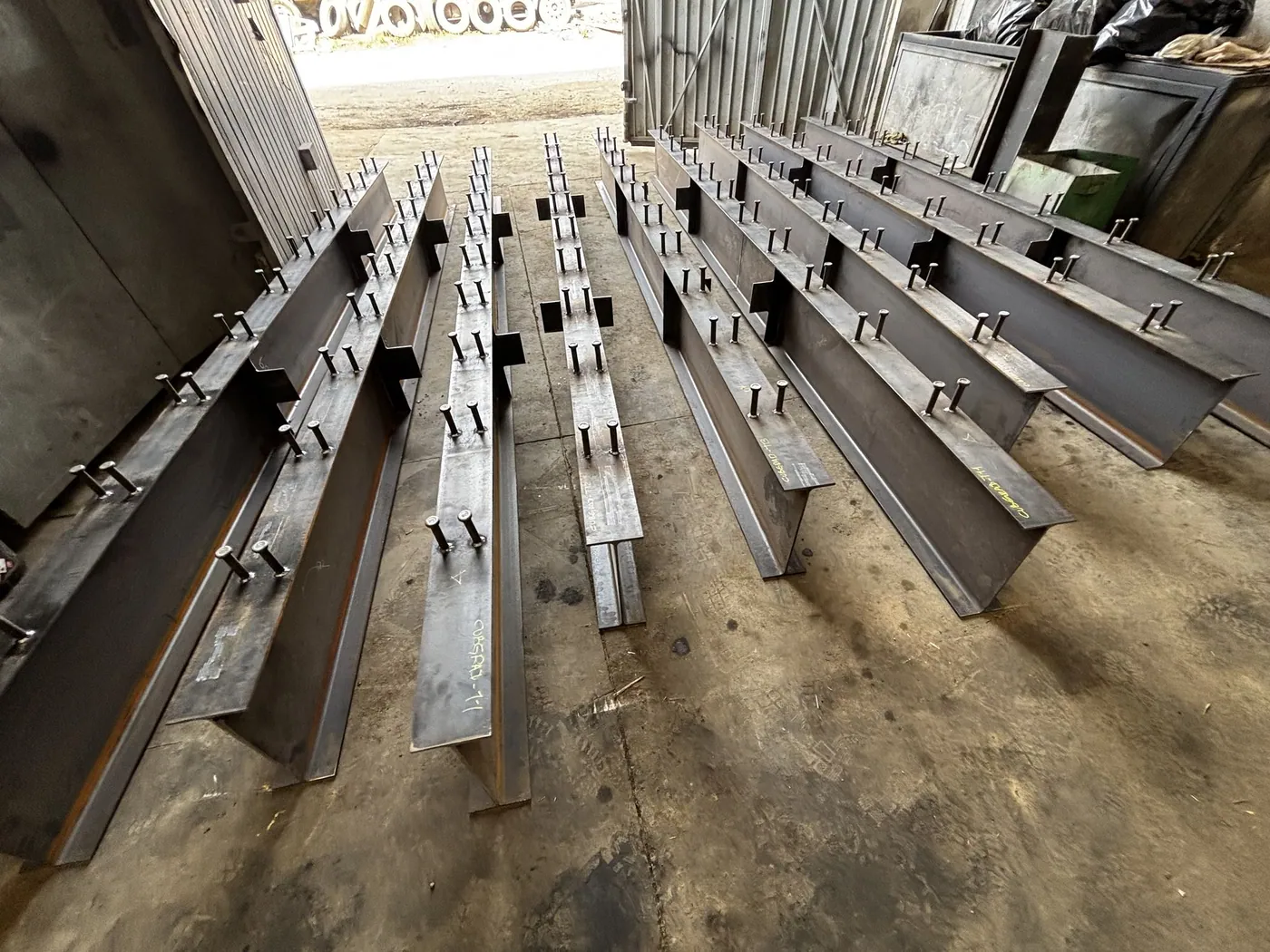 Piezas de estructura metálica fabricadas y alineadas en el piso del taller